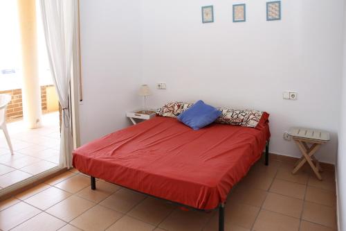 een slaapkamer met een bed met een rode deken bij AT038 Vistas de la playa, primera línea con piscina in Torredembarra