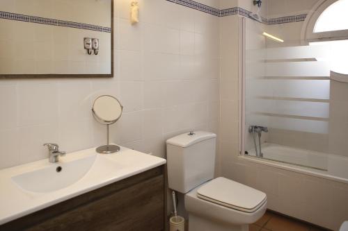 een badkamer met een toilet, een wastafel en een spiegel bij AT038 Vistas de la playa, primera línea con piscina in Torredembarra