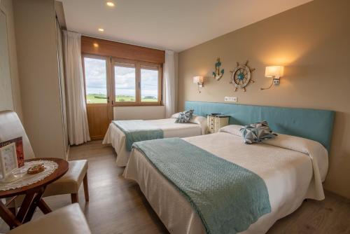 a hotel room with two beds and a table at Hotel el Pinar in Villapedre