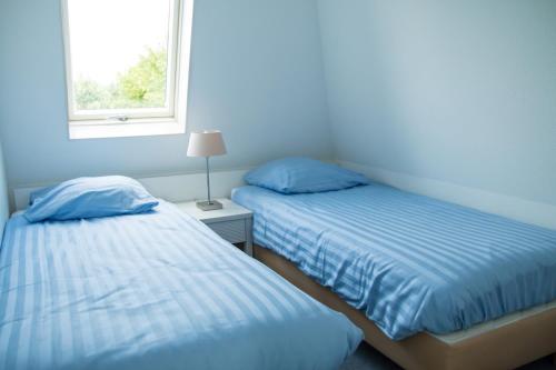 2 camas en una habitación con ventana en Bungalow 6p en Noordwijk