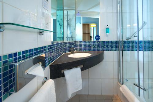 a bathroom with a sink and a glass shower at Holiday Inn Express Stevenage, an IHG Hotel in Stevenage