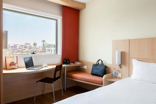 a hotel room with a desk with a laptop and a window at Ibis Antananarivo Ankorondrano in Antananarivo