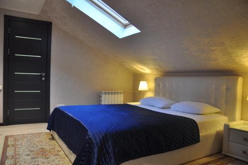 a bedroom with a bed with a blue blanket and a skylight at Blue Marine Hotel in Adler