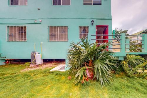 a blue house with a palm tree in front of it at Palmetto#1 @ Island Cabanas in Caye Caulker