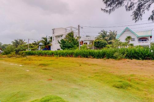 a house on a grassy hill with houses in the background at Palmetto#1 @ Island Cabanas in Caye Caulker