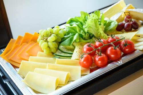 a tray of cheese and vegetables and tomatoes and grapes at Hotel Olympia Schießanlage in Garching bei München