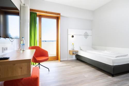 een slaapkamer met een bed, een bureau en een stoel bij Hotel Olympia Schießanlage in Garching bei München