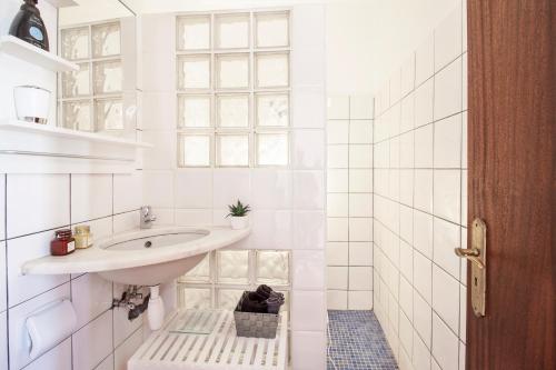 a white bathroom with a sink and a window at Casa Oceano-Mar a vista in Raposeira