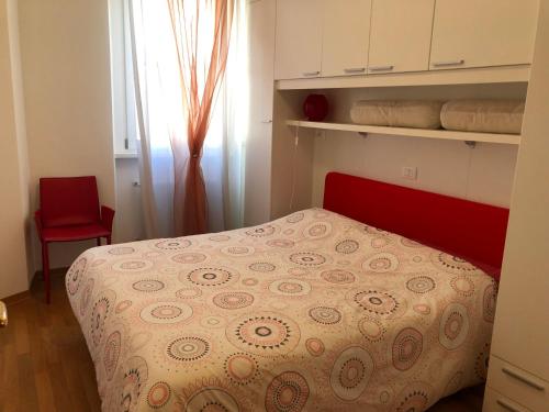 a small bedroom with a bed and a red chair at Calle Corbatto in Grado