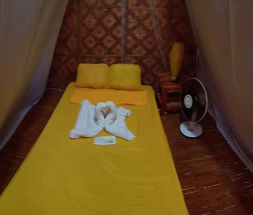 a room with a yellow bed with towels on it at SHUKRAN Apartelle in Siquijor