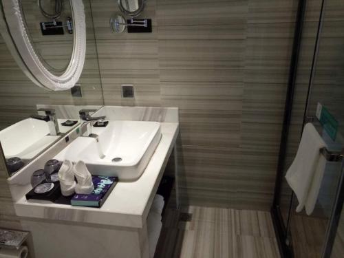 a bathroom with a sink and a mirror at Xana Hotelle Hangzhou Xiaoshan International Airport in Hangzhou