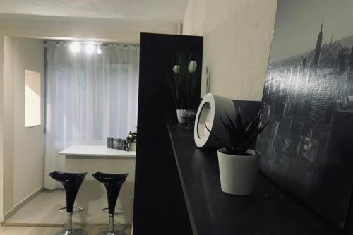 una habitación con un mostrador negro con dos taburetes negros en REEAS APARTAMENT, en Timisoara