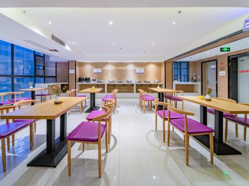 a restaurant with wooden tables and purple chairs at Lavande Hotels·Guiyaung North Railway Station in Guiyang