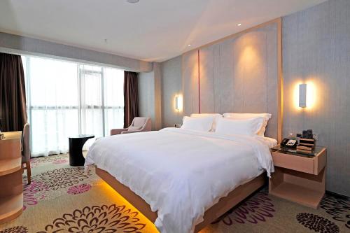 a bedroom with a large white bed and a large window at Lavande Hotels·Guiyaung North Railway Station in Guiyang