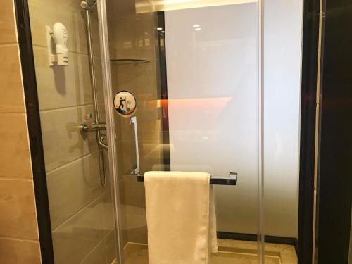 a shower with a glass door and a towel at 7Days Premium Guiyang North Station in Guiyang