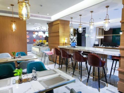 a restaurant with tables and chairs and a bar at Magnotel guiyang fountain commercial center subway station hotel in Guiyang