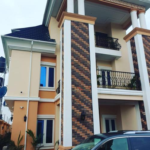 a house with a car parked in front of it at Mexiloyd Luxury Rooms & Suites in Port Harcourt