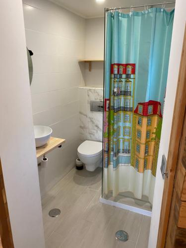 a bathroom with a shower curtain with a toilet at Casinha Azul near Meco Beach in Sesimbra