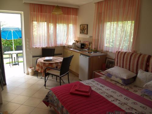 a bedroom with a bed and a table and a kitchen at Villa Verde Apart-Hotel in Nea Makri