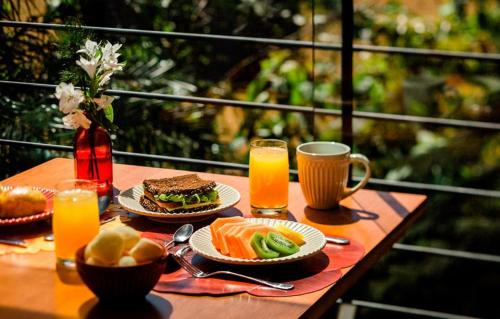 une table avec des assiettes de nourriture et des tasses de jus d'orange dans l'établissement Kayrós Business Hotel, à Jaraguá do Sul
