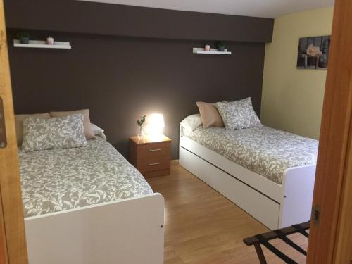 1 dormitorio con 2 camas y mesita de noche con lámpara en Apartamentos Turísticos Clavero 2, en Plasencia