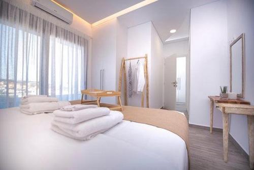 a white room with two beds with towels on them at Emmeleia mare in Agia Pelagia