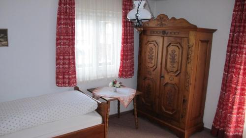 a bedroom with a bed and a wooden cabinet and a table at Pension Zillnhäusl in Schönau am Königssee
