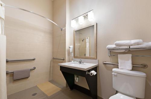 a bathroom with a sink and a toilet and a mirror at Residency Suites in Cotulla