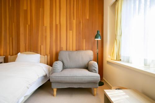 a bedroom with a chair and a bed at Ryosha Tsukiakari in Yamanakako