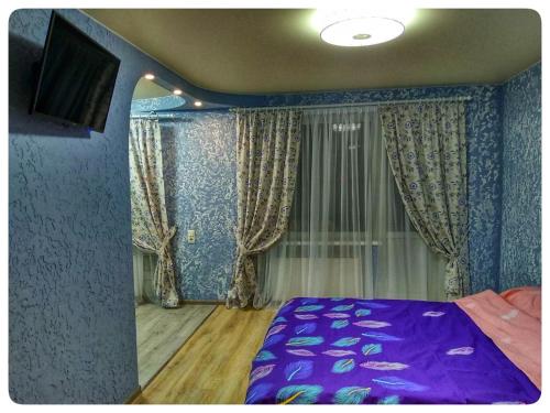 1 Schlafzimmer mit einem lila Bett und einem TV in der Unterkunft 2х кімнатна квартира на вулиці Лесі Українки in Uzyn