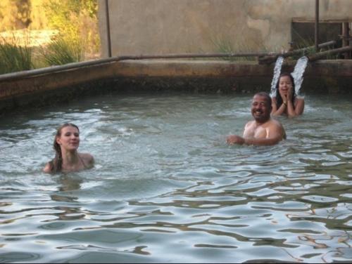 three people are swimming in a swimming pool at Badry Sahara Camp in Bawiti