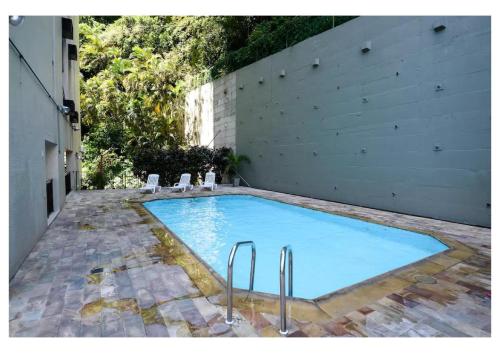 a swimming pool with two chairs and a building at Real Residence Hotel in Rio de Janeiro