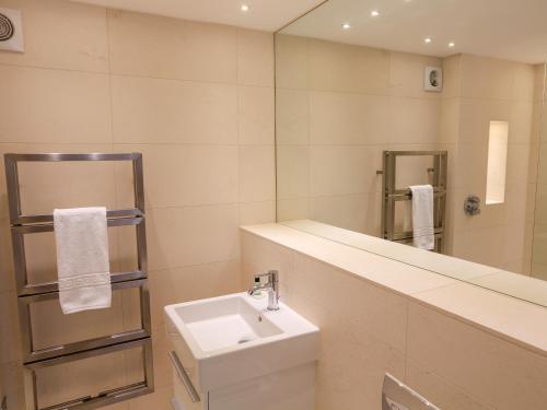 a white bathroom with a sink and a mirror at Courtenay Villa in Salcombe