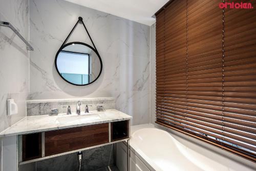 a bathroom with a tub and a sink and a mirror at Brown-Dot Hotel Shinho in Busan