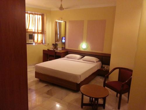 a bedroom with a bed and a table and a chair at Hotel Ashray International, Sion - Near BKC in Mumbai