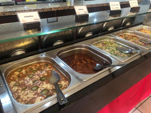 Una línea de buffet con varias bandejas de comida en El Camino Hotel & Suites, en Heroica Caborca