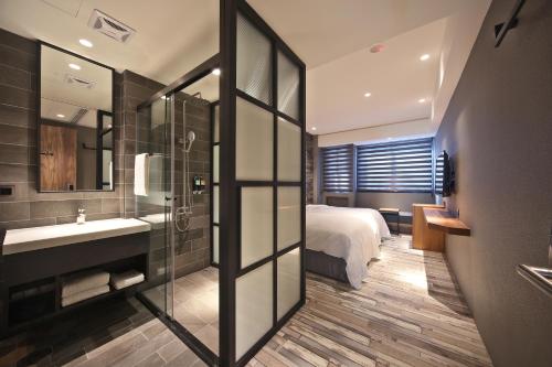 a bathroom with a bed and a sink and a mirror at Fengjia Micro Hotel in Taichung