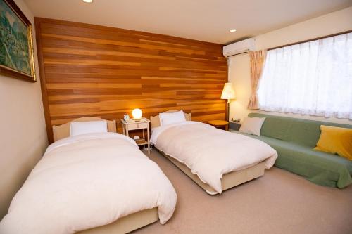 a bedroom with two beds and a couch and a window at Ryosha Tsukiakari in Yamanakako