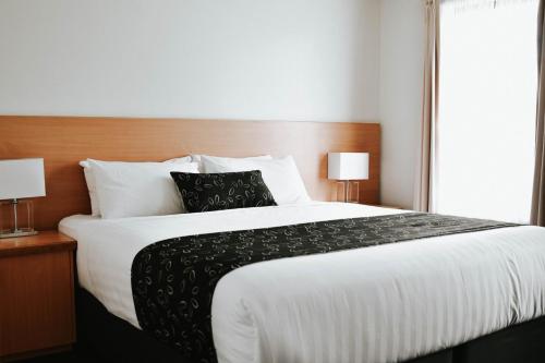 a bedroom with a large bed with two lamps at The Charles in Wagga Wagga