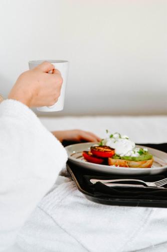 a person holding a plate of food on a bed at The Charles in Wagga Wagga