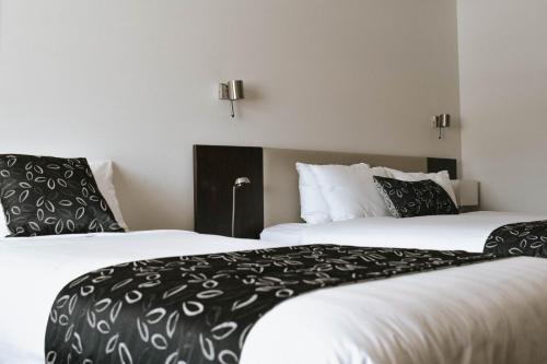 two beds with black and white pillows in a hotel room at The Charles in Wagga Wagga