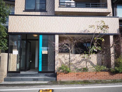 a building with a blue door on a street at Riverside TABI-NE in Kanazawa