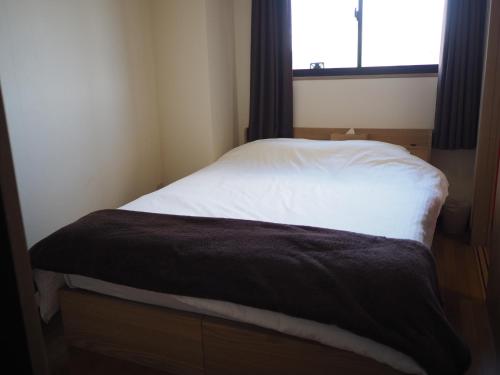 a bed in a small room with a window at Riverside TABI-NE in Kanazawa