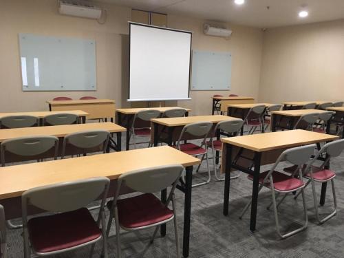 an empty classroom with tables and chairs and a whiteboard at Choice City Hotel in Surabaya