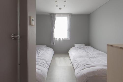 two beds in a room with a window at Crasco TABI-NE in Kanazawa