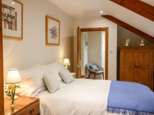 ein Schlafzimmer mit einem weißen Bett und einem Stuhl in der Unterkunft Court Prior Cottage in Totnes