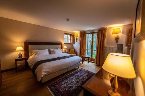 a bedroom with a large bed and a table with a lamp at Auberge Saint Walfrid Hôtel Restaurant & Spa in Sarreguemines
