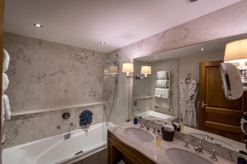 a bathroom with two sinks and a tub and a mirror at Auberge Saint Walfrid Hôtel Restaurant & Spa in Sarreguemines