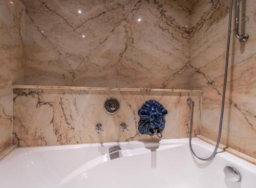 a bathroom with a bath tub with a mask on the wall at Auberge Saint Walfrid Hôtel Restaurant & Spa in Sarreguemines