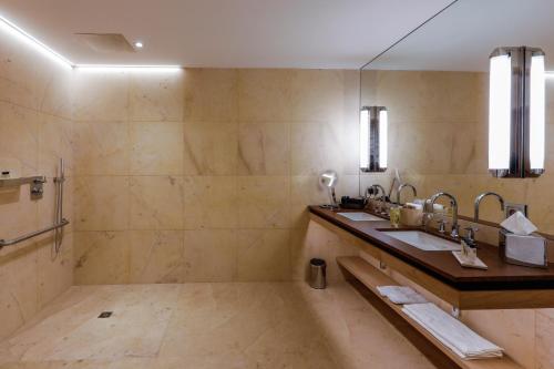 a bathroom with two sinks and a shower at Auberge Saint Walfrid Hôtel Restaurant & Spa in Sarreguemines